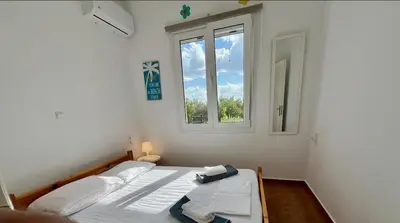 a white bedroom with a bed and a window at Stay Salty - Two Different Houses in Marathi