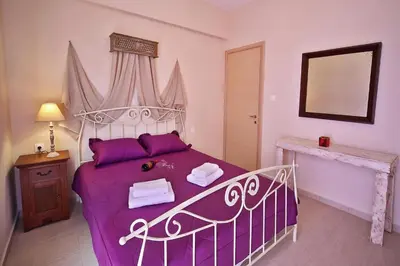 a bedroom with a large bed with purple sheets at Sfakia Thea Apartments in Sfakiá