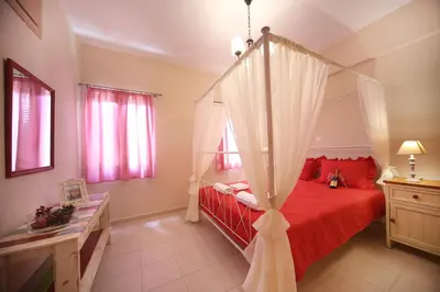 a bedroom with a red bed with a canopy at Sfakia Thea Apartments in Sfakiá