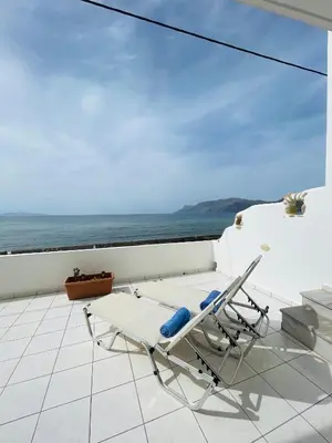 a lounge chair on a balcony with a view of the ocean at Waves House in Kissamos