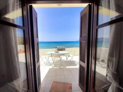 an open door to the beach with a table and chairs at Waves House in Kissamos