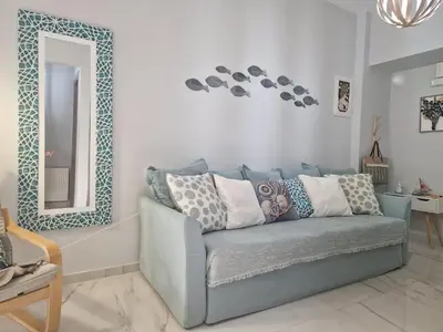 a living room with a blue couch and a mirror at E&G Relax Homes-E in Kissamos