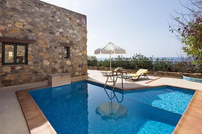 a swimming pool with a table and an umbrella at Meliti Sunset View & Private Pool Villa 20 min from Elafonissi in Livadia