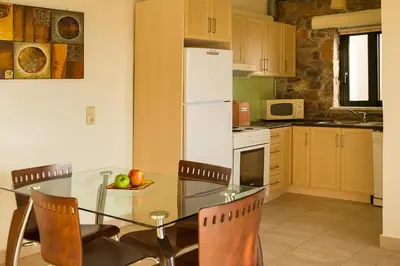 a kitchen with a glass table with chairs and a refrigerator at Meliti Sunset View & Private Pool Villa 20 min from Elafonissi in Livadia