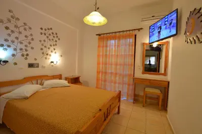 a bedroom with a bed and a tv on the wall at Kochyli Studios in Palaiochóra