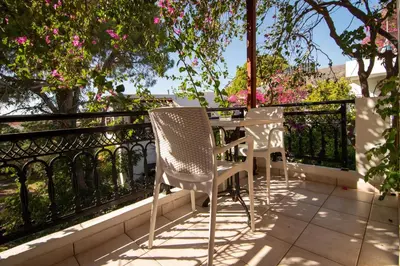 two chairs and a table on a balcony with pink flowers at Virginia Studios in Palaiochóra