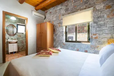 a bedroom with a white bed and a stone wall at Charming Villa in Gerani Chanion