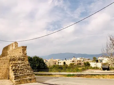 an old stone wall with a city in the background at Anastasia’s House in Kissamos