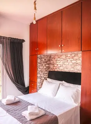 a bedroom with a bed with wooden cabinets and towels at Rafaellas Apartment in Chania Town