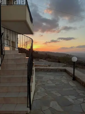 a building with stairs and a sunset in the background at Panos Village in Maláxa