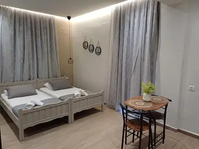a bedroom with two beds and a table in it at Romeos Studios in Agia Marina Nea Kydonias
