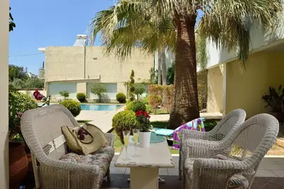 a patio with two chairs and a table and a palm tree at Alexandra's Relaxing Suite in Kalamaki Chanion