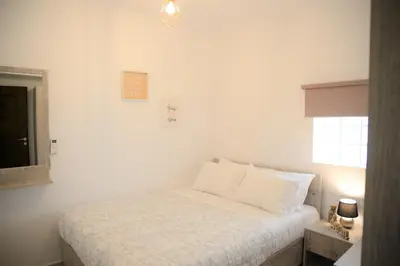 a bedroom with a bed with white sheets and a window at Iconic Chania in Chania Town
