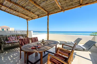a patio with a table and chairs on the beach at Ilias Apartments in Plataniás