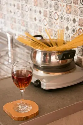 a glass of wine sitting on a counter with a pot of pasta at Ilias Apartments in Plataniás