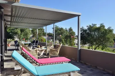 a patio with chairs and a table on a deck at Alexandra's Garden Houses in Stalos