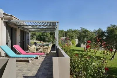 a patio with chairs and a table in a garden at Alexandra's Garden Houses in Stalos