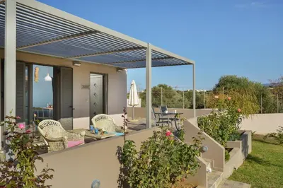 a house with a patio with chairs and a table at Alexandra's Garden Houses in Stalos