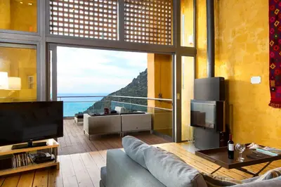 a living room with a couch and a large window at Athina Epavlis - Ethereal Charm of Blue Horizons in Ravdhoúkha