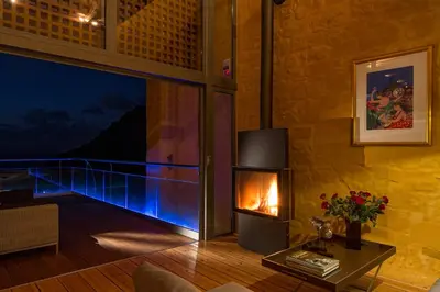 a living room with a fireplace and a balcony at Athina Epavlis - Ethereal Charm of Blue Horizons in Ravdhoúkha