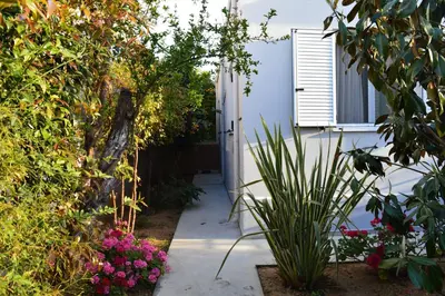 a garden with pink flowers and a white building at casa Marilia in Chania Town