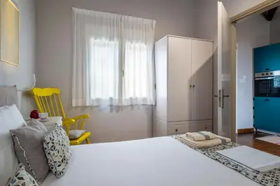a bedroom with a white bed and a yellow chair at Casa Chrysa Chania 1st floor house with amazing view in Galatás