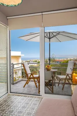 a balcony with a table and an umbrella at Casa Chrysa Chania 1st floor house with amazing view in Galatás
