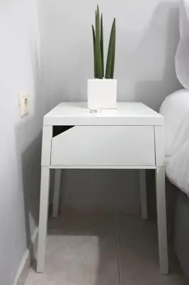 a white bedside table with a potted plant on it at Rita's home in Chania Town