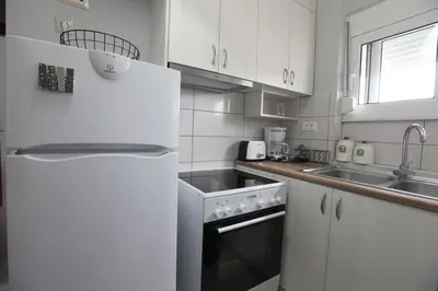 a white kitchen with a sink and a refrigerator at Rita's home in Chania Town