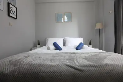 a white bed with blue pillows in a bedroom at Rita's home in Chania Town