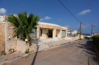 a house with a palm tree next to a street at Sandy Suites in Kalamaki Chanion