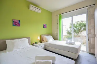 two beds in a room with green walls and a window at Villa Nopigia Mare in Kissamos