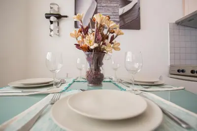 a table with plates and glasses and a vase of flowers at Casa de Campo 1 in Almirida
