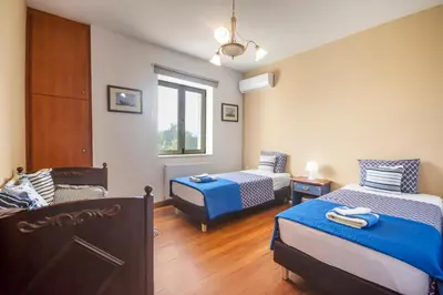 a room with two beds and a chair in it at Orange Tree Garden vacation home in Ayiá