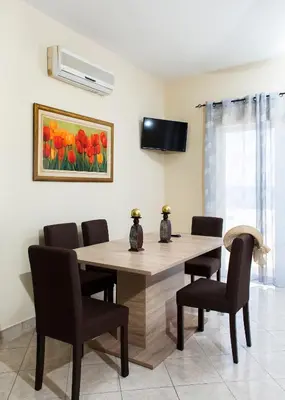 a dining room table with chairs and a painting of tulips at Mavros Molos Seaside Apartment in Kissamos