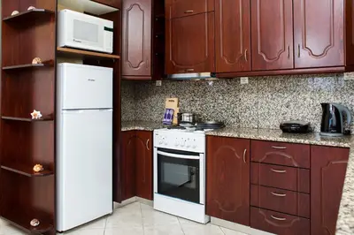 a kitchen with wooden cabinets and a white refrigerator at Mavros Molos Seaside Apartment in Kissamos
