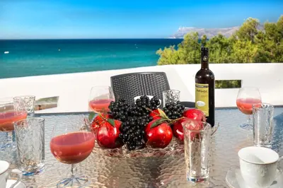 a table with a bottle of wine and a bowl of fruit at Mavros Molos Seaside Apartment in Kissamos