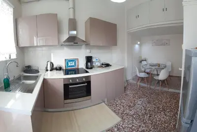 a kitchen with white counters and a sink and a table at Sunday Apartment Chania 2A in Chania Town