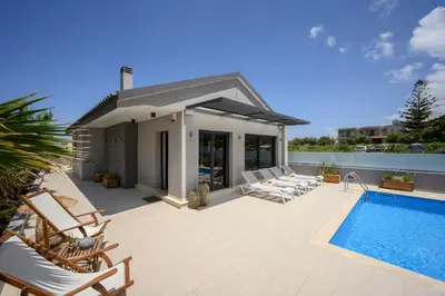 a patio with chairs and a swimming pool at Sun Ray Beach Life Villa in Agia Marina Nea Kydonias