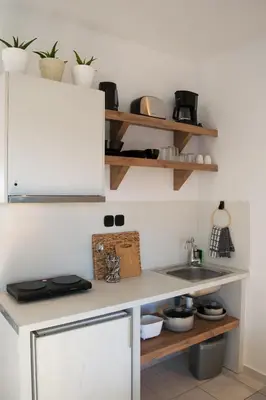 a kitchen with a counter with a sink and shelves at Kanso Rooms in Galatás