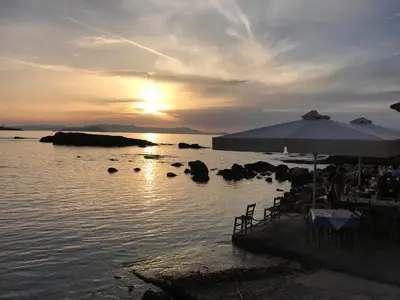 a beach with a table and an umbrella in the water at Microcosmos Halepas in Chania Town
