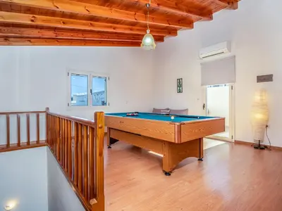 a pool table in a living room with a staircase at Casteli Stone Residence in Kissamos