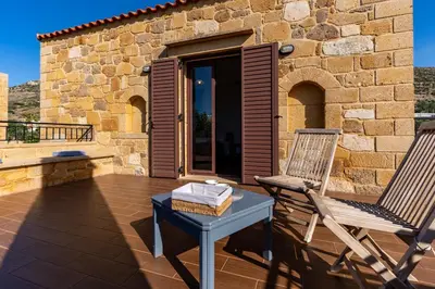 a patio with two chairs and a table and a building at Stay in Falassarna Villas in Falasarna