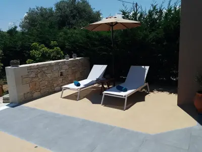two chairs and an umbrella on a patio at Chania Olive Home in Kato Daratso