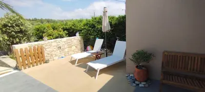 a patio with two chairs and a table and an umbrella at Chania Olive Home in Kato Daratso