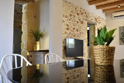 a dining room with a table and a tv on a stone wall at The Well in Chania Town