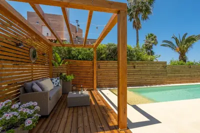 a wooden deck with a pergola next to a swimming pool at Chania Elite Homes, Enjoy a Chic Oasis by the heated Pool in Kounoupidhianá
