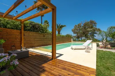 a patio with a pool and a wooden pergola at Chania Elite Homes, Enjoy a Chic Oasis by the heated Pool in Kounoupidhianá