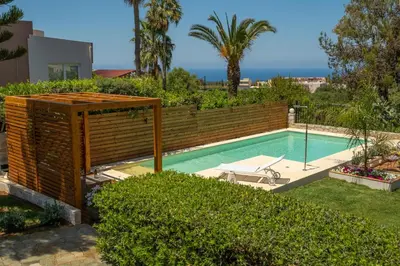 a swimming pool in a backyard with a wooden fence at Chania Elite Homes, Enjoy a Chic Oasis by the heated Pool in Kounoupidhianá