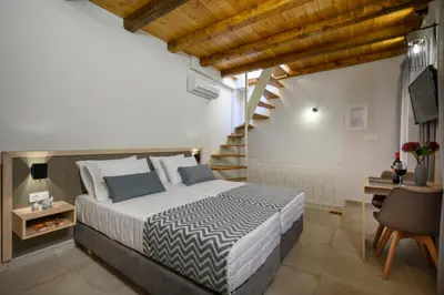 a bedroom with a large bed and a staircase at Penny's Old Town Houses in Chania Town